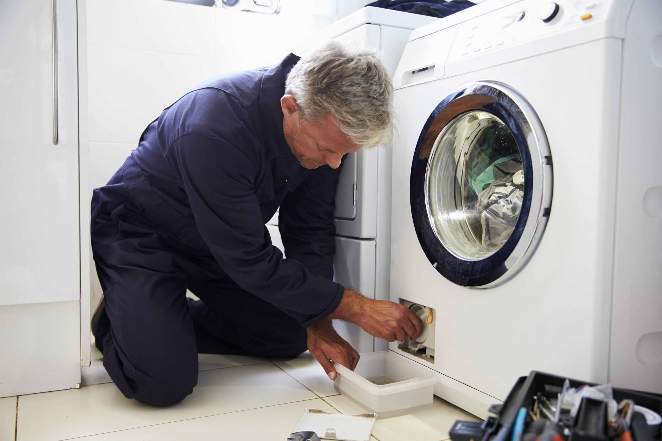 Washing machine technician removing drain filter